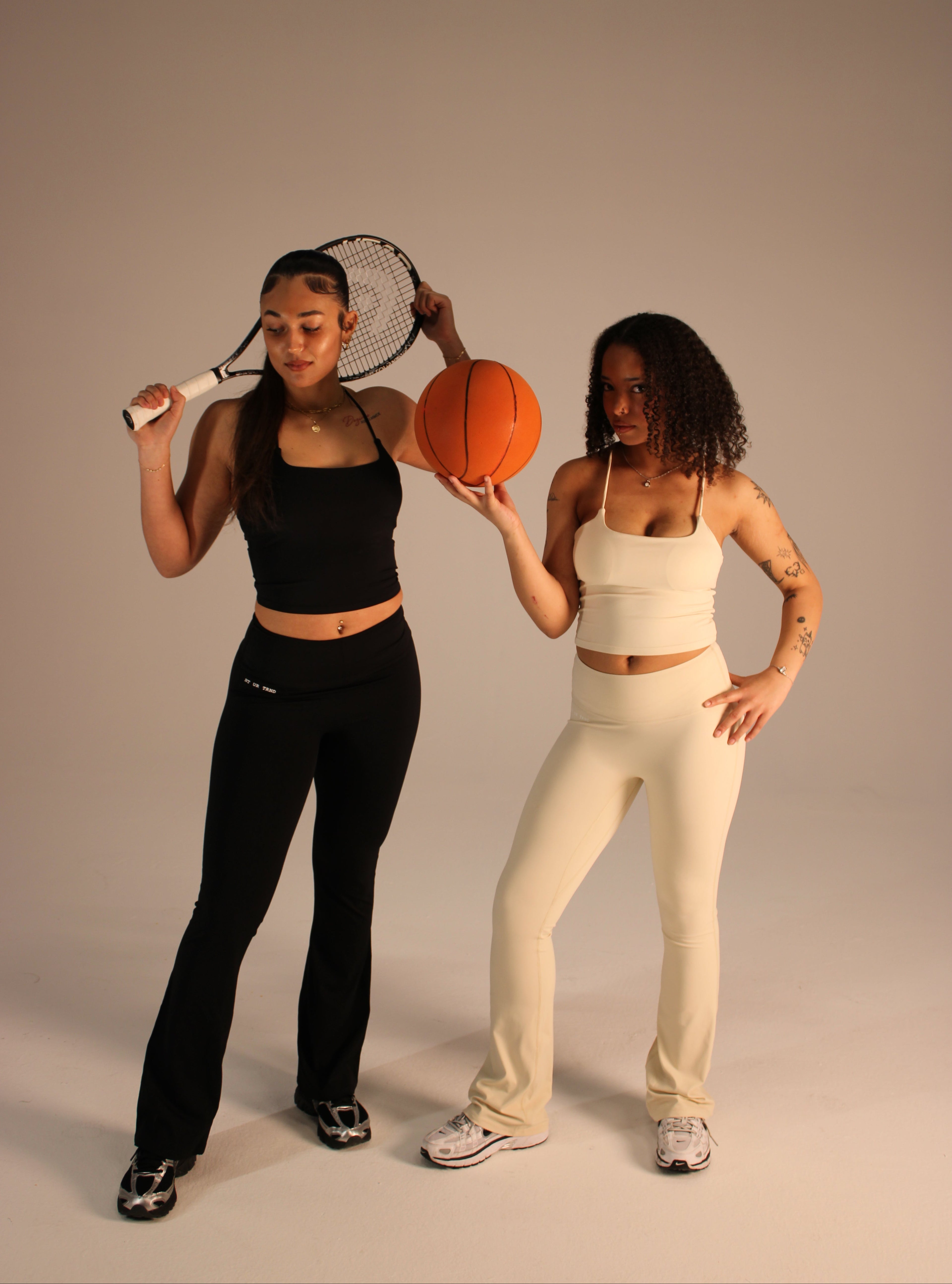 Two women playing basketball from a top-down perspective on a plain background