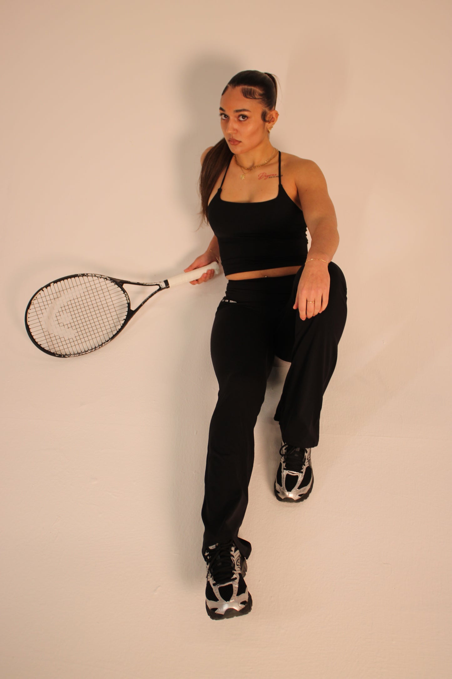 Person holding a tennis racket against a plain background