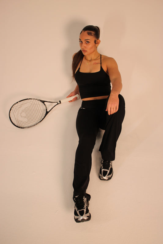 Person holding a tennis racket against a plain background